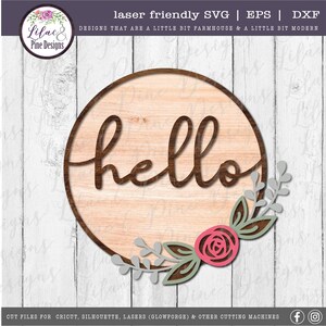 May include: A round wooden sign with the word "hello" in a cursive font. The sign is decorated with a floral wreath with pink and green leaves.