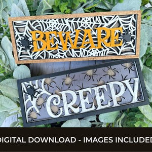May include: Two Halloween-themed wooden signs. The top sign reads "BEWARE" in orange letters, set against a white spiderweb design. The bottom sign says "CREEPY" in white, with spider accents. The text "DIGITAL DOWNLOAD - IMAGES INCLUDED" is at the bottom.
