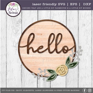 May include: A round wooden sign with the word "hello" in a brown cursive font. The sign is decorated with a yellow flower and green leaves.