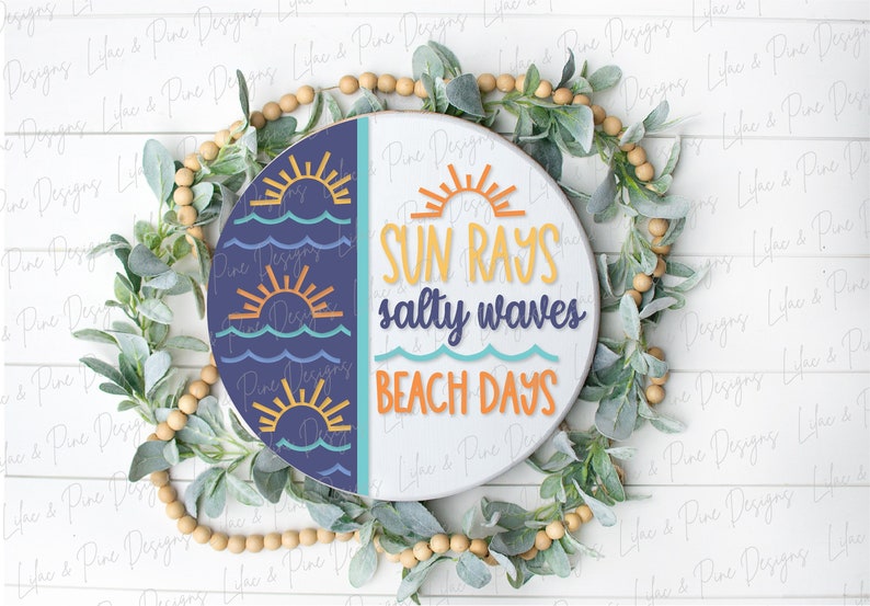Op de afbeelding: Een rond houten bord met een blauwe en witte achtergrond. De linkerzijde heeft een patroon van oranje zonnen en blauwe golven. De rechterzijde heeft de tekst "SUN RAYS salty waves BEACH DAYS" in oranje, gele en blauwe letters.