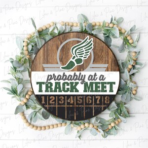 May include: A round wooden sign with a track and field theme. The sign features a green and white winged shoe graphic and the text "probably at a TRACK MEET". Numbers 1-8 are displayed below.