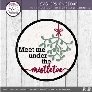 May include: A circular design with a black border features the text "Meet me under the mistletoe." The design includes a sprig of green mistletoe with berries and a red bow. The design is for cutting machines.