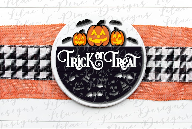 K&ouml;nnte beinhalten: Ein rundes schwarz-wei&szlig;es Schild mit dem Text "Trick or Treat" in wei&szlig;en Buchstaben. Drei orangefarbene K&uuml;rbisgesichter befinden sich oben auf dem Schild, umgeben von fliegenden Flederm&auml;usen.