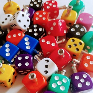 Puede incluir: Una colección de dados coloridos con diferentes números de puntos en cada lado. Los dados están hechos de plástico y tienen un pequeño agujero en la parte superior para una cuerda o cinta. Los dados son una adición divertida y colorida a cualquier proyecto de artesanía o juego.