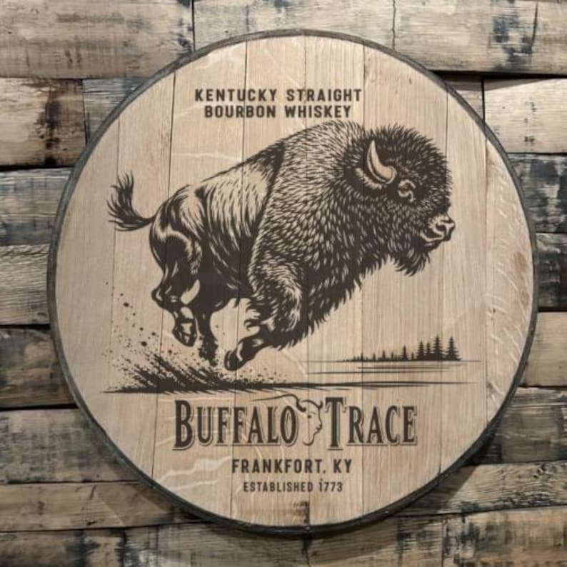 May include: A round wooden sign with a dark metal rim. The sign features a detailed illustration of a bison in motion, with the text "Kentucky Straight Bourbon Whiskey" at the top. The words "Buffalo Trace" are prominently displayed below the bison.