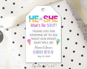 May include: A white gift tag with the text "HE or SHE What's The SCOOP?" and "GENDER REVEAL" in colorful fonts. The tag is 2" x 3.5" and includes ice cream cone graphics. The tag is on a gift wrapped in white paper with black polka dots.