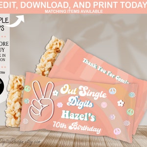 Pode incluir: Sacos de lembrancinhas cor de pêssego com um sinal de paz e o texto "Out Single Digits Hazel's 10th Birthday". Os sacos têm um design de arco-íris e as palavras "Thank You For Coming". Guloseimas de arroz crocante são visíveis.