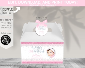 May include: A white gable box with a pink bow and a circular tag. The box is decorated with pink glitter and snowflake accents, and features the text "Winter ONEderland" and a photo of a baby. The box measures 3.25" x 5.75".