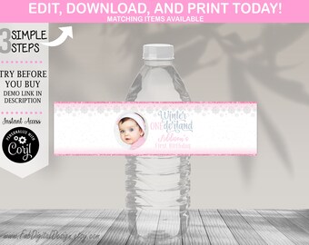 Peut inclure: Une bouteille d'eau avec une étiquette personnalisée. L'étiquette présente une photo de bébé et le texte "Winter ONEdrland, Addison's First Birthday." L'étiquette a un design de flocon de neige rose et blanc, avec le texte "Edit, Download, and Print Today!" en haut.