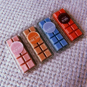 May include: Four wax melts in clear packaging with different scents. The scents are "Sweet Tooth", "Caramel Dream", "The Espresso", and "Cherry Baby".