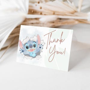 May include: A blue and white cartoon character, Stitch, peeks out of a hole in a white background. The text "Thank You!" is written in brown cursive on a green background.