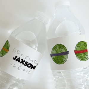 Op de afbeelding: Twee doorzichtige plastic waterflessen met gepersonaliseerde etiketten. De etiketten hebben een ontwerp van een groene schildpaden schild met een paarse en rode band. Een etiket zegt "Let's Party Jackson is five!"