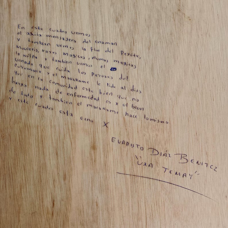 Może przedstawiać: Jasna drewniana deska z odręcznym tekstem wykonanym ciemnym tuszem. Napis zawiera szczeg&oacute;łową hiszpańską narrację o symbolach duchowych oraz podpis Evaristo D&iacute;az Benitez z tytułem Uxa Temay podkreślonym poniżej.