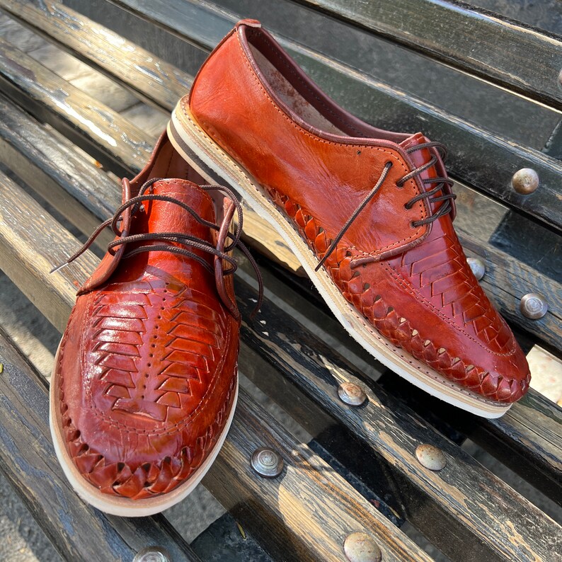 May include: A pair of brown leather shoes with woven detailing. The shoes have a lace-up closure and a white sole.