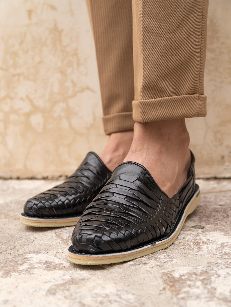 May include: Black leather woven slip-on shoes with a white sole.