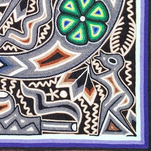 May include: A textile wall hanging featuring intricate embroidery on a black background. The design includes a stylized grey figure, a vibrant green flower with blue accents, and geometric patterns in white, brown, and grey thread.