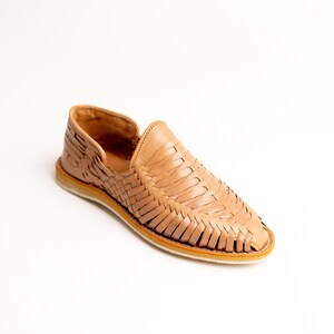 May include: A tan leather woven loafer shoe. The shoe features a slip-on design with a woven upper and a light-colored sole. The shoe is made of leather and has a classic, casual style.