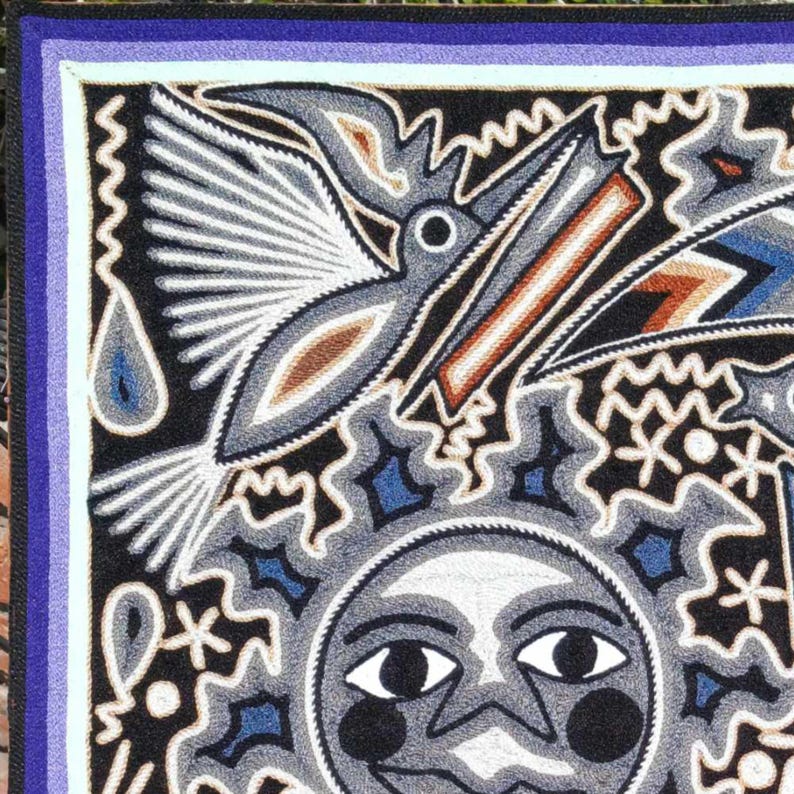 May include: A rectangular textile wall hanging featuring a central sun face with human-like features, surrounded by a flying bird and abstract geometric patterns. The design uses a palette of black, white, blue, and brown yarn on a dark background.