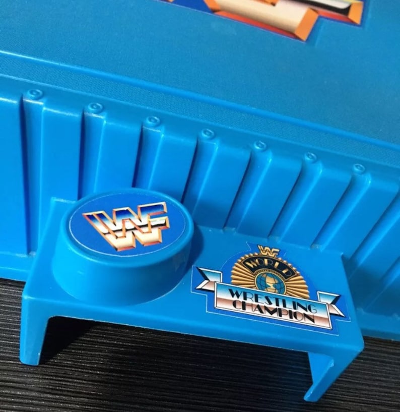 May include: Blue plastic wrestling ring toy with a WWF logo and "World Wrestling Champion" text.