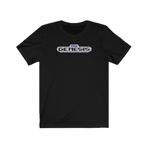 Op de afbeelding: Zwart T-shirt met een wit en blauw Sega Genesis-logo met de tekst "SEGA GENESIS VIDEO ENTERTAINMENT SYSTEM".