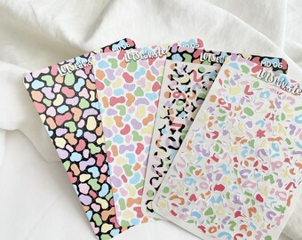 Puede incluir: Cuatro hojas de pegatinas con patrones coloridos con el texto "Lots of Love, Stef" y "MD 06" impreso en ellas. Las pegatinas presentan una variedad de formas y diseños abstractos en rosa, azul, verde, amarillo y naranja.