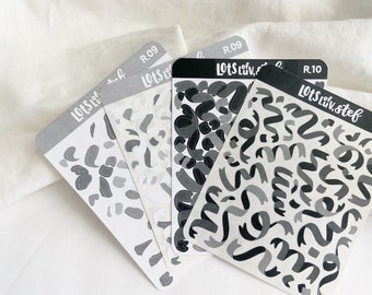 Puede incluir: Cuatro hojas de pegatinas con patrones en blanco y negro. Las pegatinas están diseñadas con formas abstractas y remolinos. Las hojas están etiquetadas con "Lots of Luv, Stef" y "R.09" o "R.10".