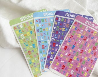 Puede incluir: Cuatro hojas de pegatinas de alfabeto con letras de colores en cuadrados. Las hojas están etiquetadas "Lots Liv. 03", "Lots Liv. 04", "Lots Liv. ", y "Lots Liv. Stef MA.05".
