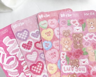 Puede incluir: Cuatro hojas rosas de pegatinas con temática de San Valentín. Las pegatinas presentan corazones, corazones de caramelo, osos y flores. El texto en las pegatinas incluye "Lots of Luv CLUB", "Cutie", "Be Mine", "Kiss Me", "Hug Me", "Luv You", "True Luv", "XOXO", y "Luv You".
