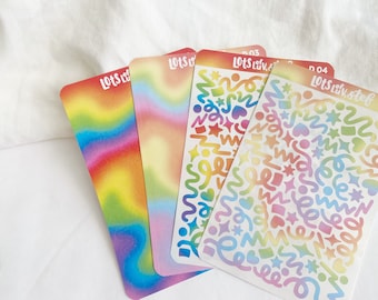 May include: Four sheets of rainbow holographic stickers with different designs. The stickers are labeled "Lots of Luv" and have a rainbow ombre effect. The designs include swirls, stars, hearts, and squares.