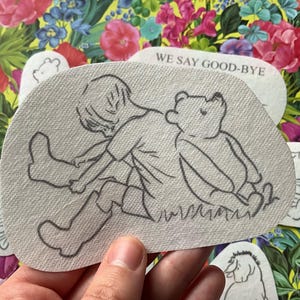 May include: A collection of Winnie the Pooh-themed patches. The main patch features a sketch of Pooh and Christopher Robin. Other patches show Pooh in various poses. One patch has the text "WE SAY GOOD-BYE". The patches are on a floral background.