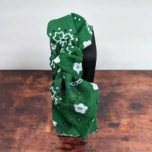 May include: Green headband with a white and black bandana print. The headband is tied in a knot at the top.
