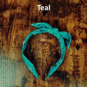 May include: Teal bandana headband with a paisley pattern. The headband is tied in a knot at the top.