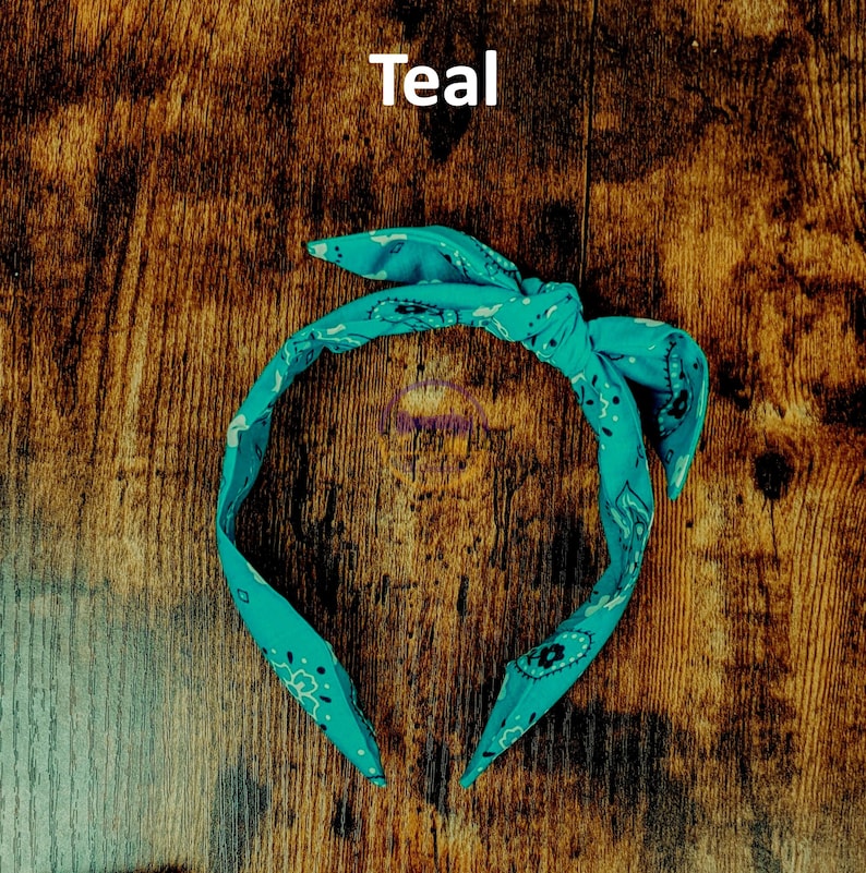 May include: Teal bandana headband with a paisley pattern. The headband is tied in a knot at the top.