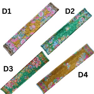 May include: Four rectangular fabric strips labeled D1, D2, D3, and D4. D1 and D4 feature a mustard yellow background with pink, blue, and white floral patterns. D2 and D3 feature a green background with similar vibrant floral and fan motifs.