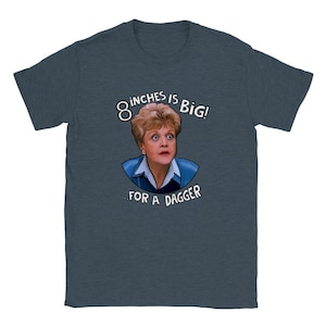 Puede incluir: Una camiseta azul oscuro con un gráfico blanco de una mujer con cabello rubio y el texto "8 inches is big! ...for a dagger."