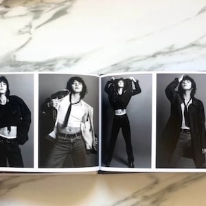 May include: A black and white photo book with four images of a person wearing different outfits. The person is wearing a black crop top, a white tank top, a black jacket, and a black coat.