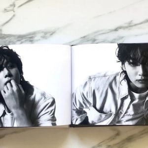 May include: A black and white photo of a person wearing a denim jacket with the text "Calvin Klein" on the front. The person is looking at the camera.