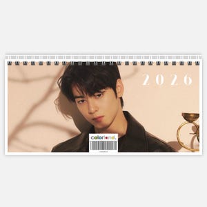 Pode incluir: Um calendário em espiral para o ano de 2026 com uma fotografia de uma pessoa com cabelo escuro e uma jaqueta preta. O calendário tem o texto "colorland." e um código de barras na parte inferior.