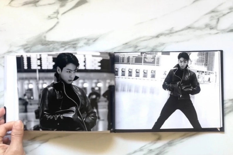 May include: A black and white photo book with two images of a person wearing a black leather jacket. The person on the left is looking to the side, while the person on the right is standing with their legs spread apart.