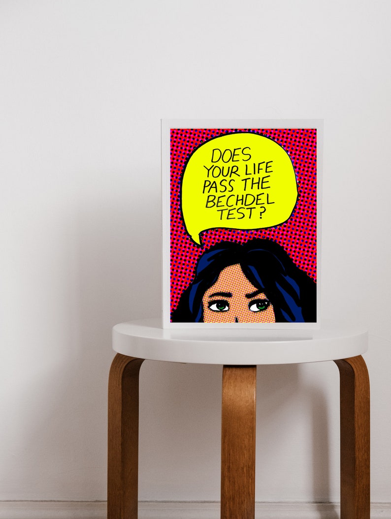 Puede incluir: Una impresi&oacute;n de arte pop enmarcada con el rostro de una mujer y un globo de di&aacute;logo que dice "Does your life pass the Bechdel test?" El fondo es rojo con lunares blancos.
