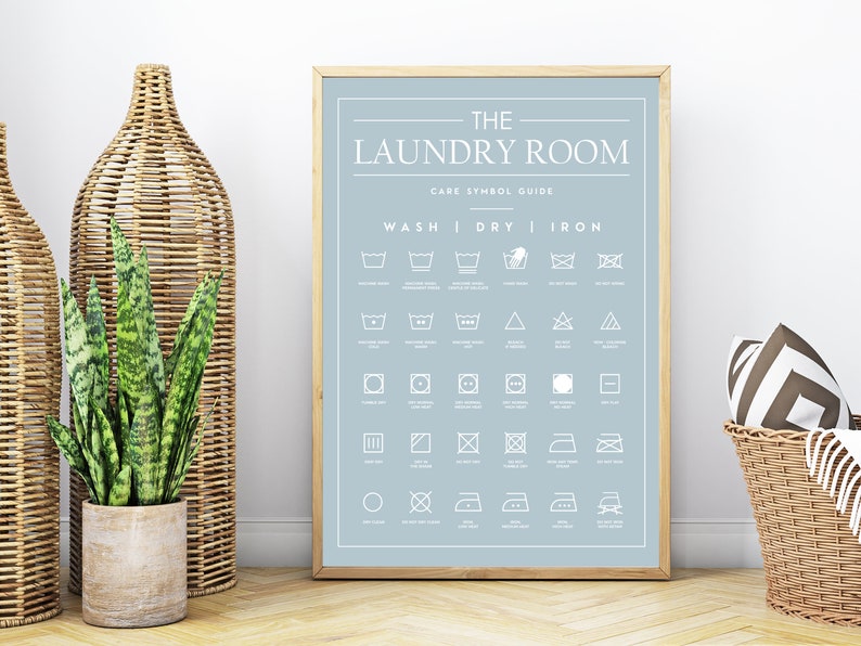Peut inclure: Une affiche encadr&eacute;e sur fond bleu clair avec le texte blanc THE LAUNDRY ROOM CARE SYMBOL GUIDE. L'impression pr&eacute;sente une grille de diverses ic&ocirc;nes d'entretien du linge class&eacute;es sous les rubriques WASH, DRY et IRON.
