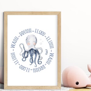 Puede incluir: Una impresión enmarcada blanca con un pulpo azul en acuarela en el centro. El pulpo tiene ocho tentáculos y está rodeado por un círculo de texto que dice "Wash - Brush - Floss - Flush - Wash - Brush - Floss - Flush".