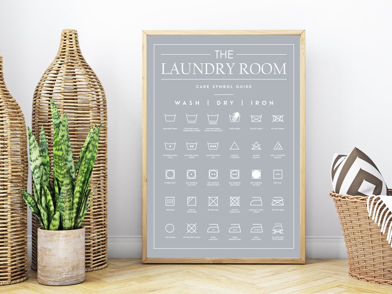 Peut inclure: Une affiche encadr&eacute;e sur fond gris clair avec du texte et des ic&ocirc;nes blancs. Le titre indique THE LAUNDRY ROOM CARE SYMBOL GUIDE, suivi d'une grille d'instructions d'entretien du linge class&eacute;es sous les rubriques WASH, DRY et IRON.