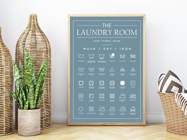 Peut inclure: Une affiche encadr&eacute;e sur fond bleu avec le texte blanc intitul&eacute; THE LAUNDRY ROOM CARE SYMBOL GUIDE. Le tableau pr&eacute;sente diverses ic&ocirc;nes de lessive pour le lavage, le s&eacute;chage et le repassage, chacune accompagn&eacute;e de sa signification en blanc.