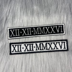 May include: Two rectangular embroidered patches featuring the Roman numerals XII-XII-MMXXVI in white thread on a black background. The top patch has white text on black, while the bottom patch features black text on a white background with a black border.