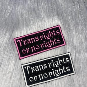 May include: Two rectangular embroidered patches. One is black with pink trim and text that reads "Trans rights or no rights." The other is black with white trim and the same text.