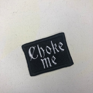 May include: Black embroidered patch with white text that reads "Choke Me".