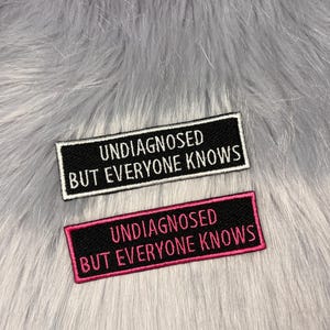 May include: Two black and white iron-on patches with white and pink embroidery. The top patch reads "Undiagnosed But Everyone Knows". The bottom patch reads "Undiagnosed But Everyone Knows".