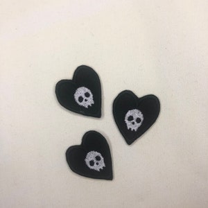 Könnte beinhalten: Drei schwarze Filz-Herz-Patches mit weißen gestickten Totenköpfen.
