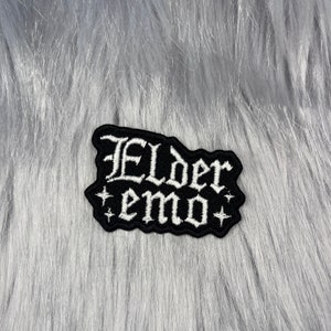 May include: Black embroidered patch with white lettering that reads "Elder emo" with two small white stars on either side.